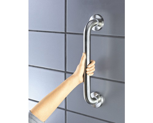 Eine Hand hält einen silberfarbenen Haltegriff im Badezimmer.