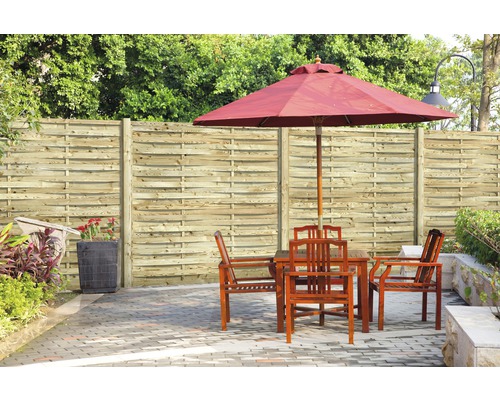 Gartenszene mit Holzzaun, Tisch, Stühlen und Sonnenschirm