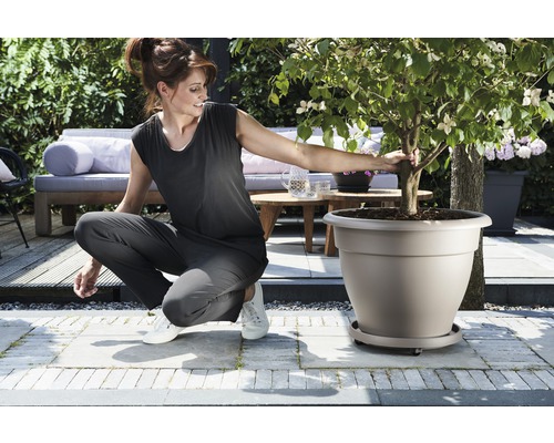 Frau hockt neben einem bepflanzten Blumentopf im Garten