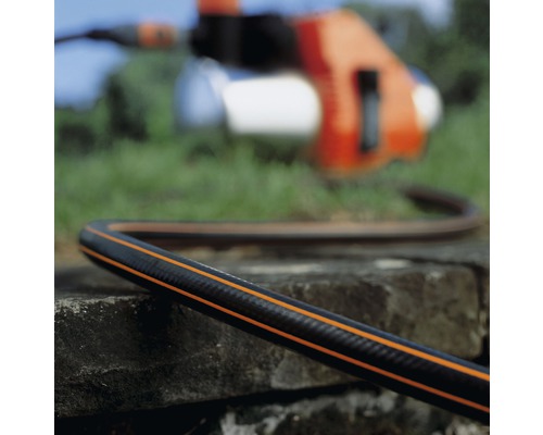 Gartenschlauch mit Bewässerungspumpe im Hintergrund