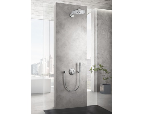 Dusche mit Kopfbrause und Handbrause an einer grauen Betonwand in einem Badezimmer.