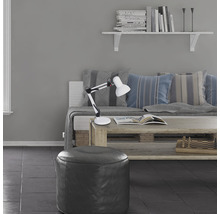 Wohnzimmer mit verstellbarer Schreibtischlampe, Couch, Kissen, Bücherregal und Sitzhocker