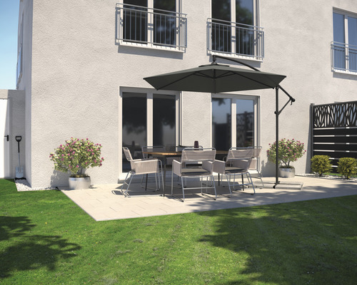 Terrasse mit Gartentisch, Stühlen und Sonnenschirm neben einem Wohnhaus.