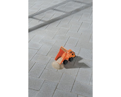 Graue Pflastersteine mit Spielzeug-Lastwagen und Sand