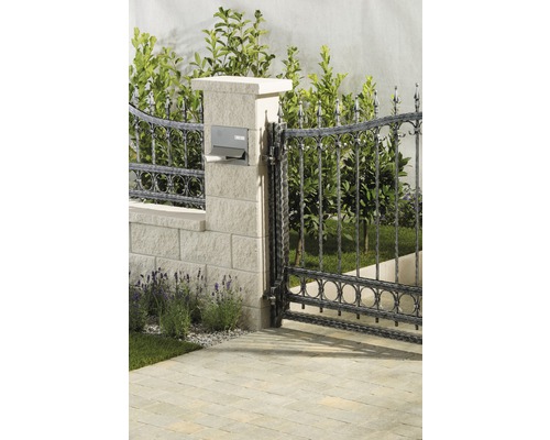 Gartenszene mit Metallzaun, Steinsäule und Briefkasten