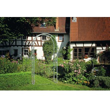 Gartenszene mit Rosenbogen aus Metall vor einem Fachwerkhaus