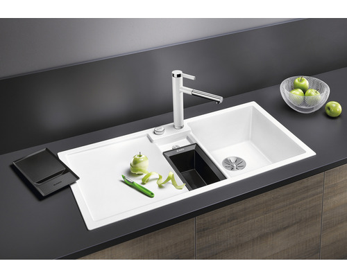 Küchenspüle mit Abtropffläche, Armatur und Zubehör auf einer Küchentheke.