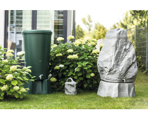 Gartenszene mit einem grünen und einem grauen Regenspeicher in Steinoptik sowie einer Gießkanne