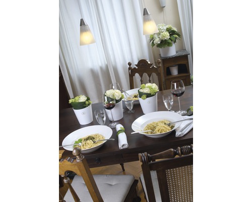 Gedeckter Esstisch mit Pasta, Blumen und Wein unter Pendelleuchten