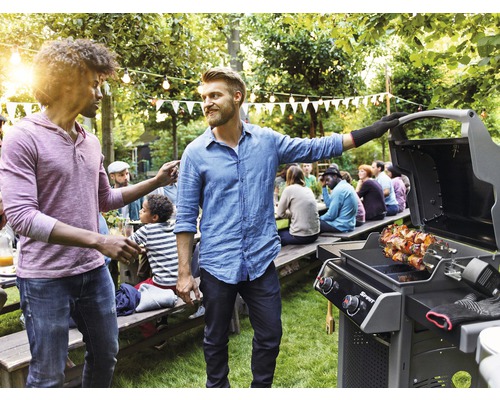 Gartenszene mit Männern am Grill und Gästen an Tischen unter Lichterketten