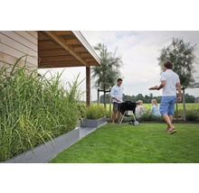 Gartenszene mit Grill, Rasen und bepflanzten Pflanzkästen