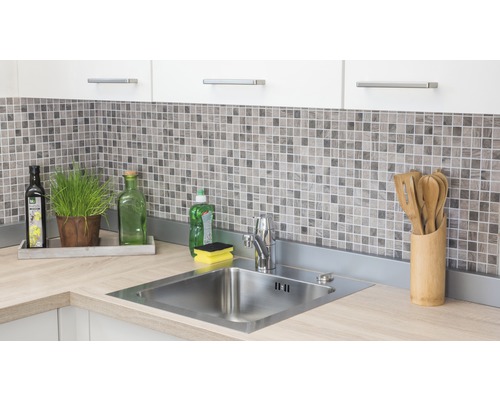 Küchenspüle aus Edelstahl mit Armatur auf einer Arbeitsplatte in einer hellen Küche mit Mosaikfliesen