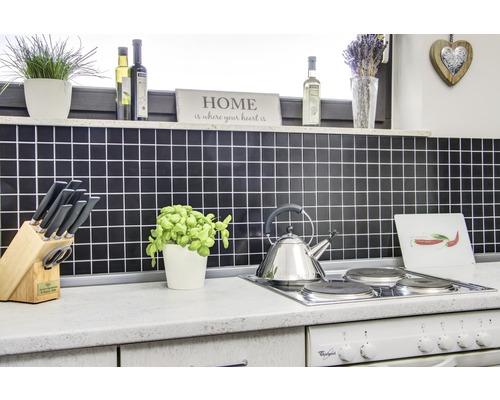 Küchenszene mit Fliesenspiegel, Kochfeld, Wasserkocher und diversen Küchenutensilien