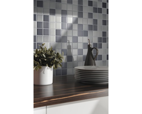 Mosaikfliesenwand über einer dunklen Arbeitsplatte mit Geschirr und Dekoration