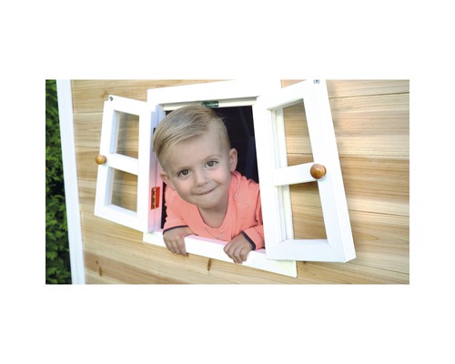 Kleiner Junge schaut aus Fenster eines Holzspielhauses