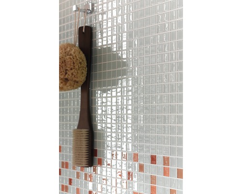 Detailaufnahme einer Wand mit Mosaikfliesen, einem Badeschwamm und einer Bürste