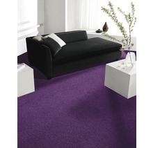 Wohnzimmer mit schwarzem Sofa, weißen Tischen und lila Teppich