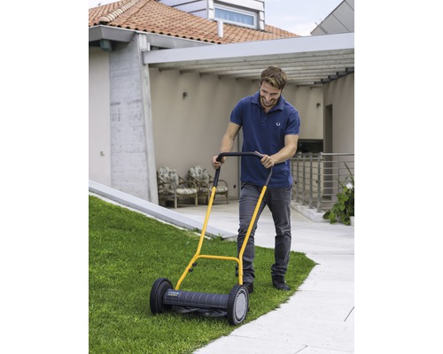 Mann benutzt Handrasenmäher im Garten