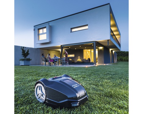 Rasenmähroboter auf Rasen vor einem modernen Haus im Freien