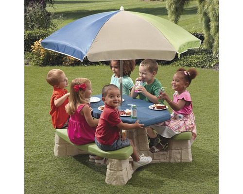Kindersitzgruppe mit Sonnenschirm auf einer Rasenfläche