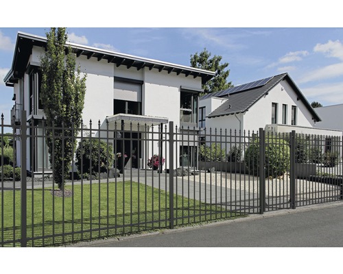 Ein schmiedeeiserner Zaun umgibt ein modernes Wohnhaus.