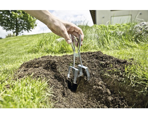 Eine Person verwendet eine Maulwurfsfalle im Garten.