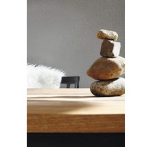 Dekorativer Steinturm auf einem Holztisch vor einer Tapete