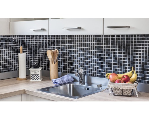 Küchenspüle mit Armatur, Arbeitsplatte, Mosaikfliesen und Küchenutensilien.