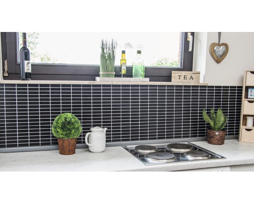 Küchenszene mit schwarzen Fliesen, Kochfeld, Fenstern und Dekorationen.