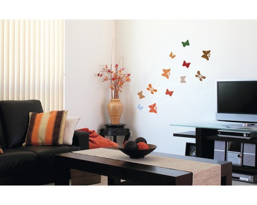 Wohnzimmer mit Sofa, Couchtisch und Wanddekoration mit Schmetterlingsmotiven.