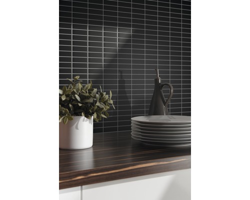 Küchenszene mit schwarzen Wandfliesen, Holzarbeitsplatte, Geschirr und Dekoration