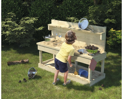Kind spielt mit einer Matschküche im Garten.