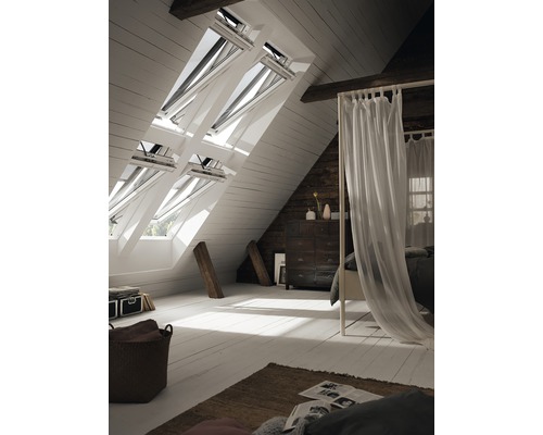 Helles Dachzimmer mit Dachfenstern, Bett und Kommode