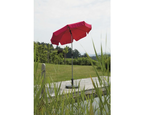 Roter Sonnenschirm auf einer Holzterrasse mit Rasen im Hintergrund.