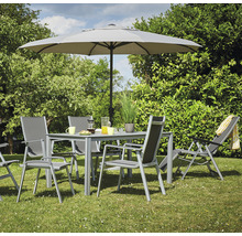 Gartenszene mit Esstisch, Stühlen, Sonnenschirm und Liegestuhl auf einer Rasenfläche