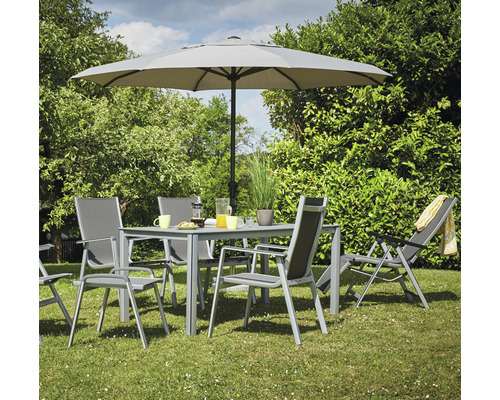 Gartenszene mit Esstisch, Stühlen, Sonnenschirm und Liegestuhl auf einer Rasenfläche