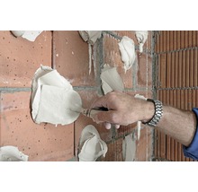 Handwerker spachtelt Ziegelwand mit einer Maurerkelle
