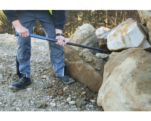 Eine Person verwendet eine Brechstange zum Bewegen von Steinen.
