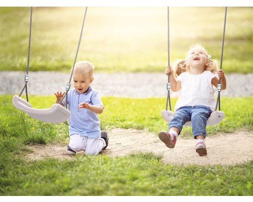 Zwei Kinder spielen auf einer Schaukel im Freien.