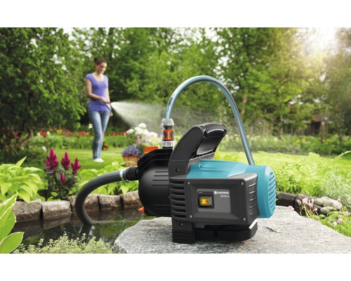 Garten mit Teich und eine Frau bewässert mit einer Gartenpumpe