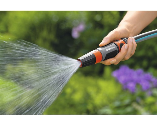 Eine Person hält einen Gartenschlauch mit Wasserstrahl in der Hand