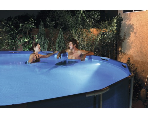 Paar entspannt in einem Aufstellpool im Garten bei Nacht.