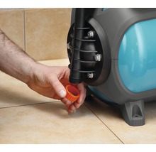 Eine Person schraubt eine orangefarbene Kappe auf eine Gartenpumpe.