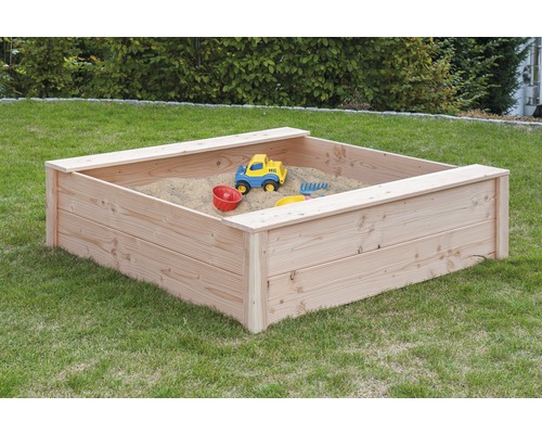 Quadratischer Sandkasten aus Holz mit Spielzeug im Garten.