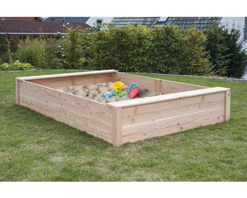 Holzsandkasten mit Spielzeug im Garten
