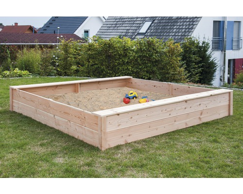Quadratischer Sandkasten aus Holz mit Spielzeug im Garten