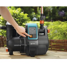 Gartenpumpe mit einer Hand am Einschaltknopf für die Wasserversorgung im Garten