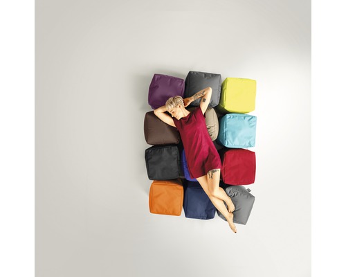 Frau ruht auf einer Anordnung von Sitzwürfeln in verschiedenen Farben