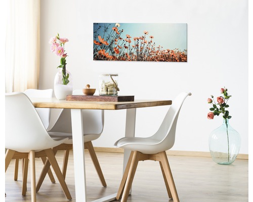 Esszimmer mit Holztisch, weißen Stühlen und Blumenbild an der Wand