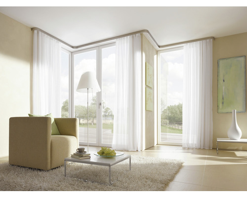 Helles Wohnzimmer mit Sessel, Teppich und weißen Vorhängen vor Fenstern